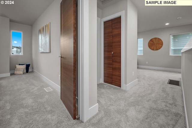 hallway with a wealth of natural light and light carpet