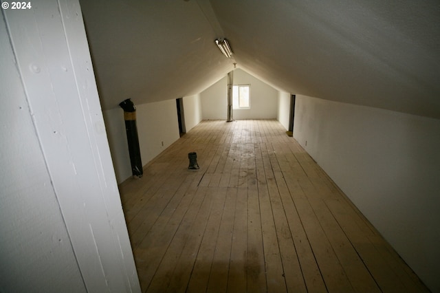 additional living space with vaulted ceiling and light hardwood / wood-style flooring