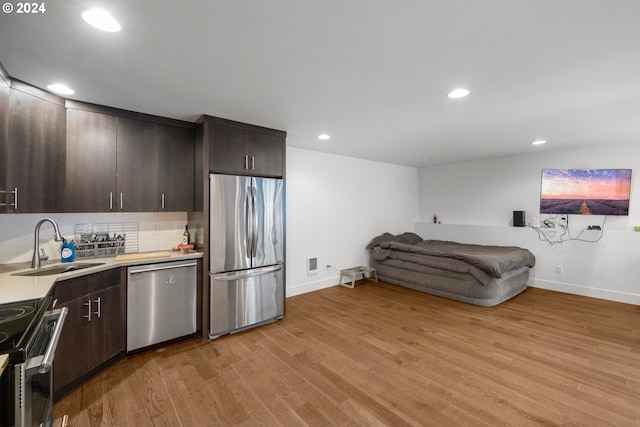 kitchen with dark brown cabinets, sink, appliances with stainless steel finishes, and light hardwood / wood-style flooring