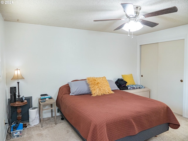 bedroom with light carpet, a closet, ceiling fan, and a textured ceiling