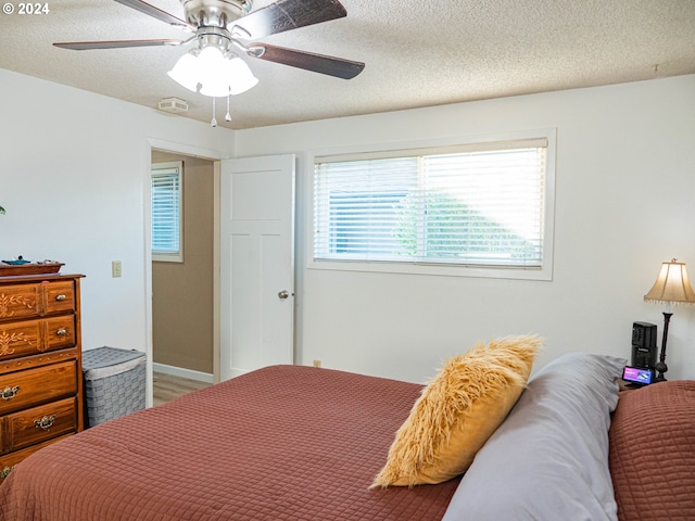 bedroom with a textured ceiling, hardwood / wood-style floors, and ceiling fan