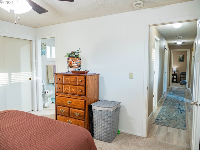 bedroom with light hardwood / wood-style flooring, ceiling fan, and a textured ceiling