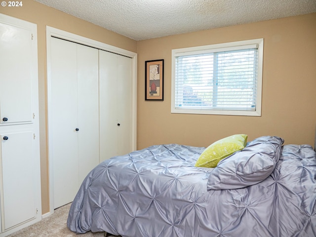 carpeted bedroom with a closet and a textured ceiling