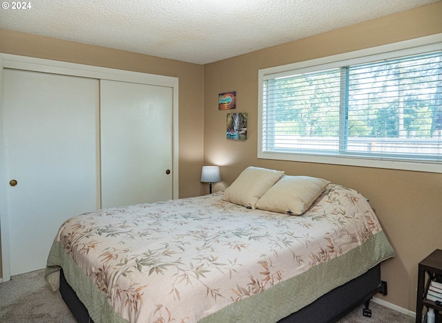 carpeted bedroom with a closet and a textured ceiling