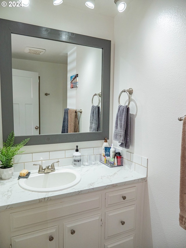 bathroom with vanity with extensive cabinet space and tasteful backsplash