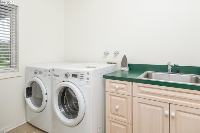 washroom with sink, washing machine and clothes dryer, and cabinets