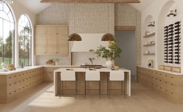 kitchen featuring light brown cabinetry, vaulted ceiling with beams, and a breakfast bar area