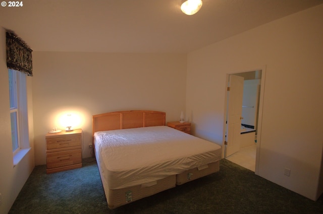 bedroom with dark colored carpet and connected bathroom