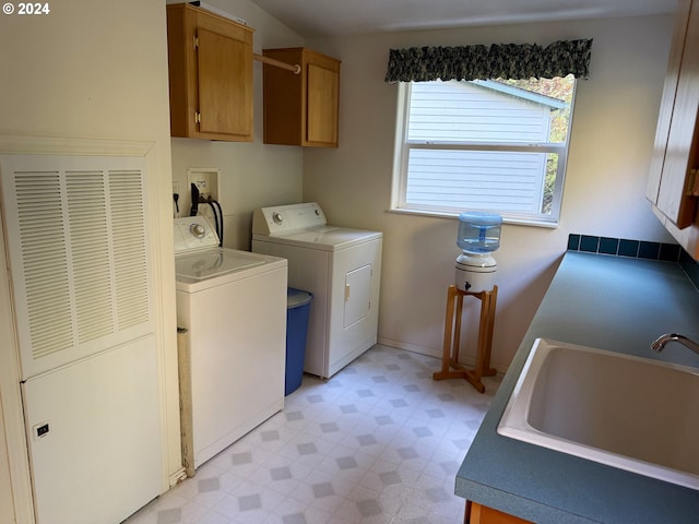 clothes washing area with cabinets, washer and clothes dryer, and sink