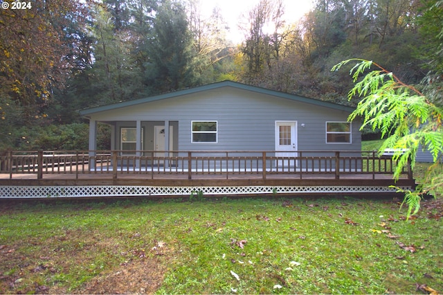 rear view of property with a wooden deck and a lawn