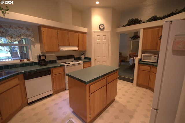 kitchen with tile counters, white appliances, and a kitchen island