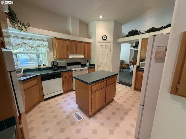 2647 S Tenmile, Lakeside, OR 97449 - kitchen with white appliances, light floors, under cabinet range hood, high vaulted ceiling, and a kitchen island