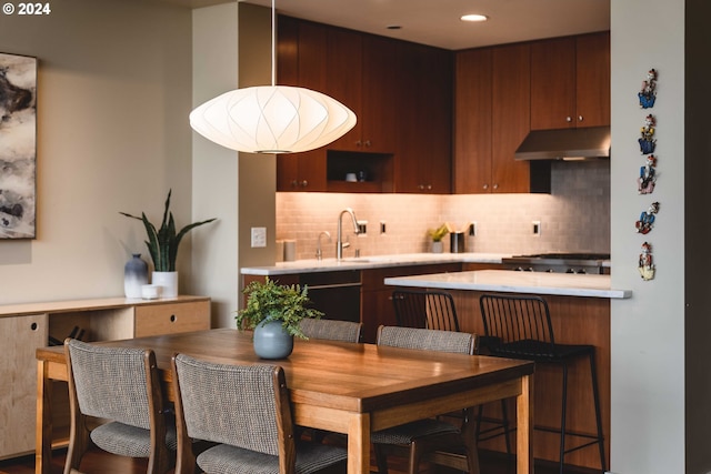 kitchen featuring stainless steel range, backsplash, sink, and kitchen peninsula