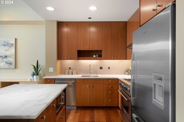 kitchen featuring hardwood / wood-style floors, stainless steel appliances, tasteful backsplash, sink, and range hood