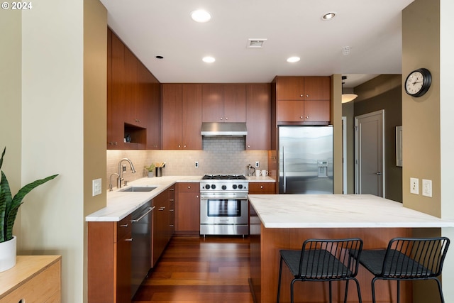 kitchen featuring decorative backsplash, dark wood-type flooring, sink, stainless steel appliances, and a kitchen bar