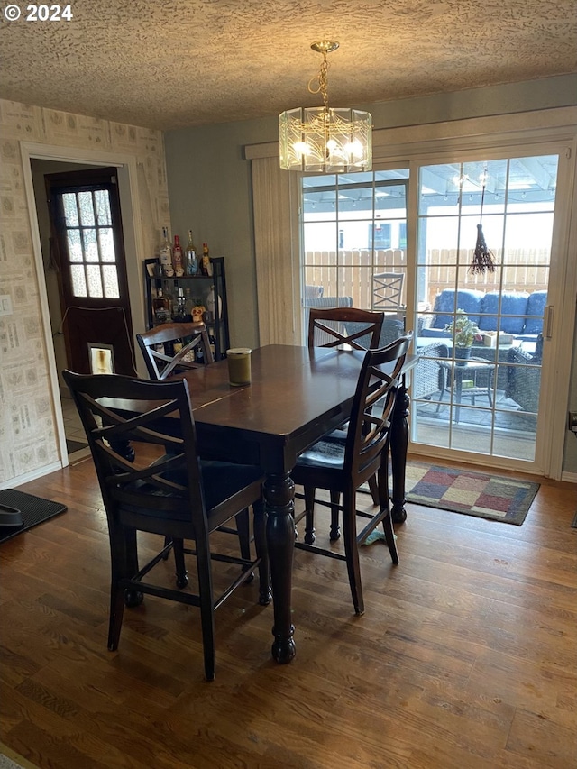 dining space with a wealth of natural light, an inviting chandelier, and dark hardwood / wood-style floors