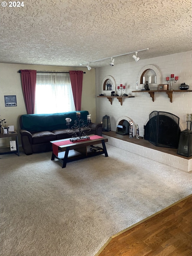 living room featuring a brick fireplace, hardwood / wood-style floors, rail lighting, and a textured ceiling