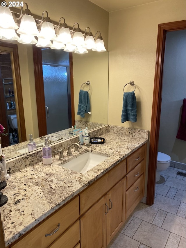 bathroom with vanity, a shower with door, and toilet