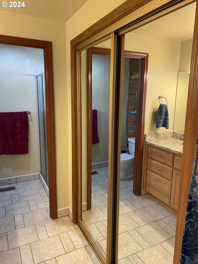 bathroom with a shower with shower door, vanity, and toilet