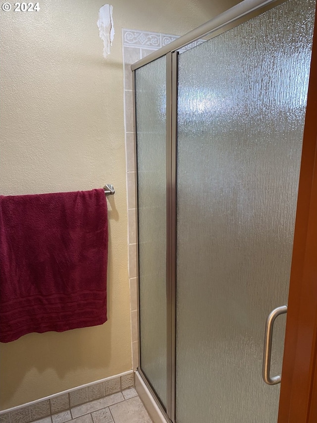 bathroom with a shower with shower door and tile patterned floors