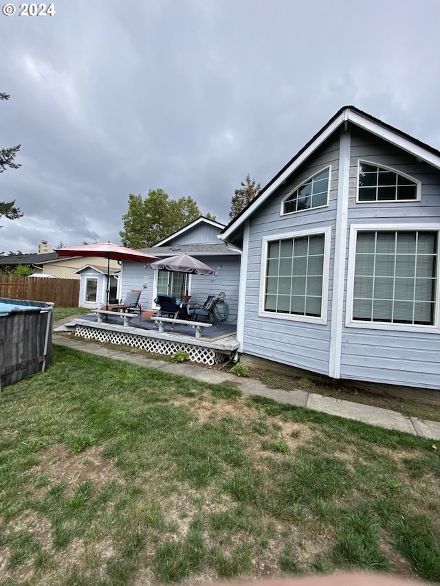 rear view of property featuring a lawn and a deck