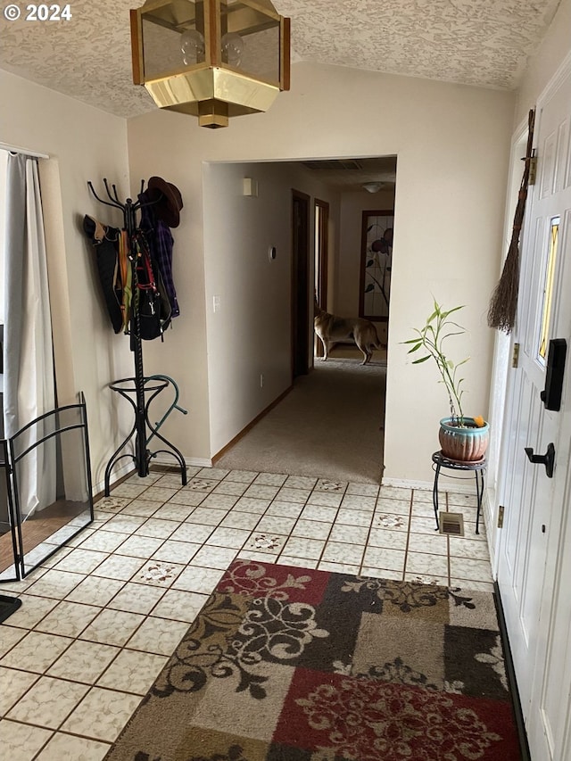 hallway featuring light colored carpet and a textured ceiling