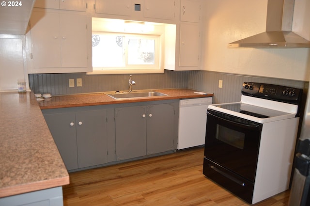705 Couch Ave, Wallowa, OR 97885 - kitchen with electric stove, wall chimney exhaust hood, white dishwasher, a sink, and a wainscoted wall