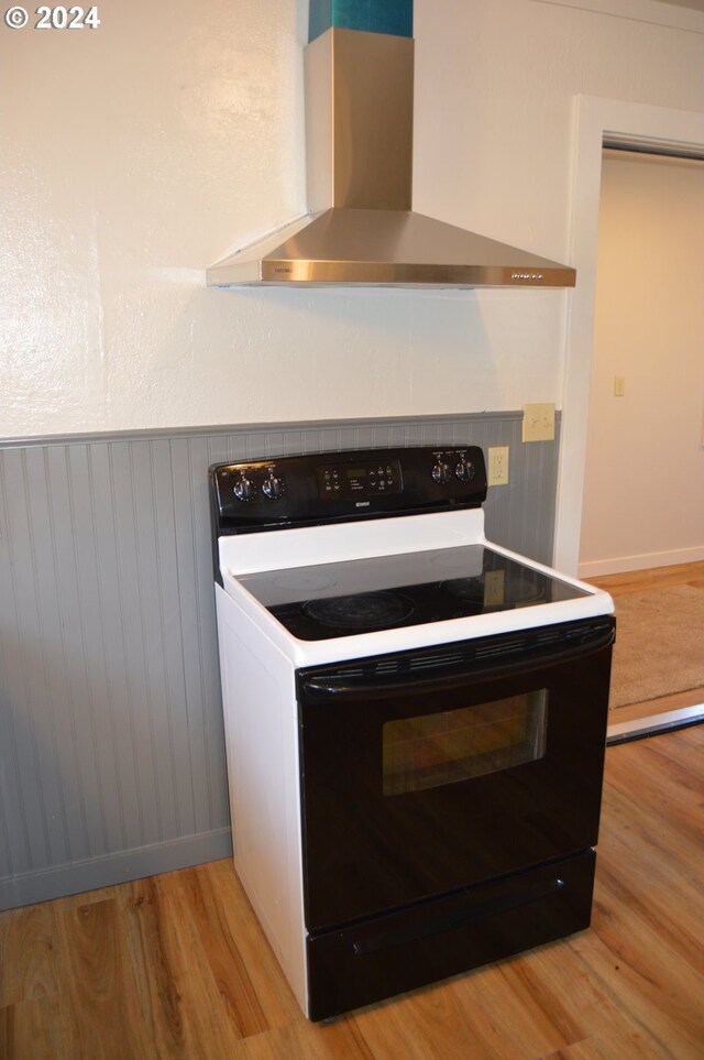 705 Couch Ave, Wallowa, OR 97885 - detailed view of black electric range oven, wall chimney range hood, and light wood-type flooring