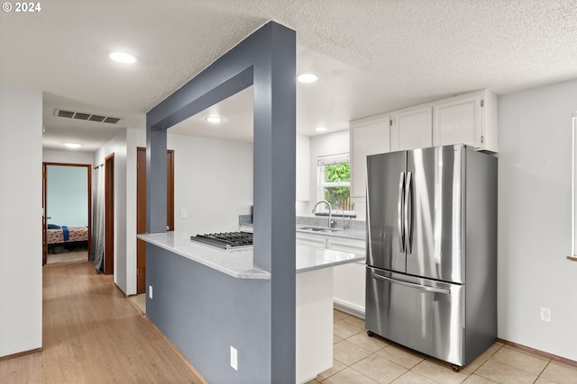 kitchen featuring sink, appliances with stainless steel finishes, white cabinetry, and light tile floors