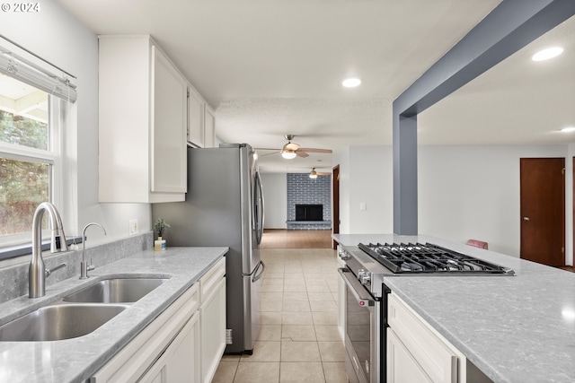 kitchen featuring high end stove, white cabinetry, light tile floors, sink, and ceiling fan