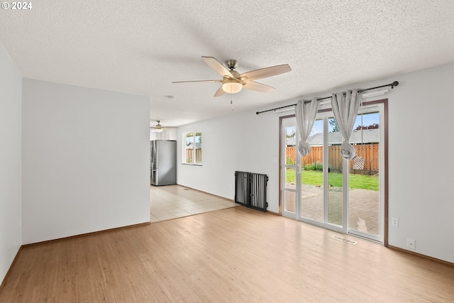 spare room with light hardwood / wood-style flooring, ceiling fan, and a textured ceiling