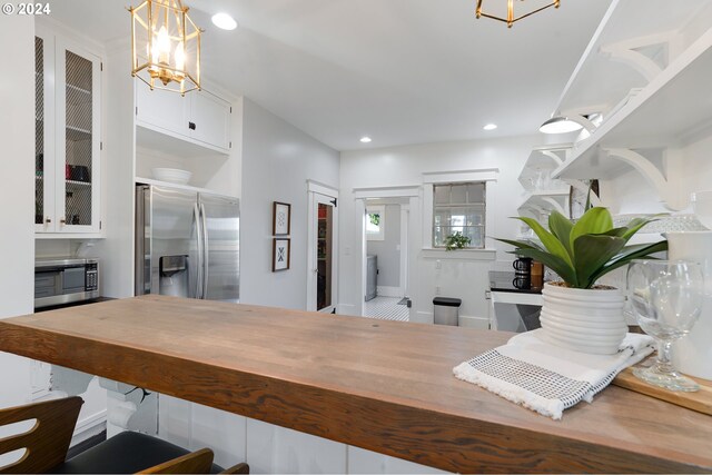 kitchen with recessed lighting, decorative light fixtures, stainless steel appliances, white cabinetry, and glass insert cabinets