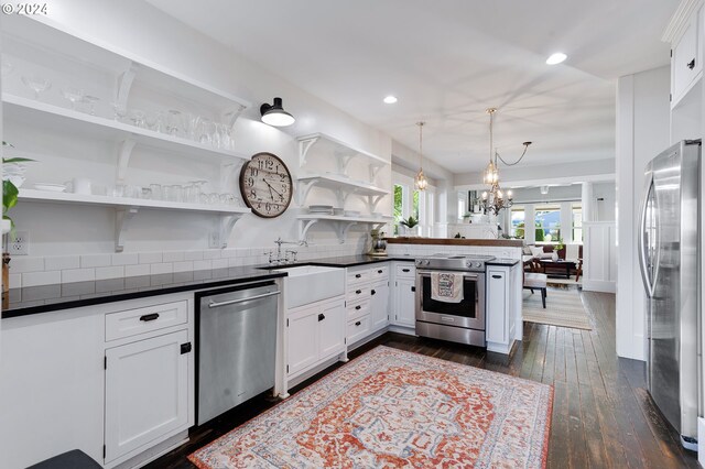 kitchen with stainless steel appliances, dark countertops, white cabinets, and a peninsula