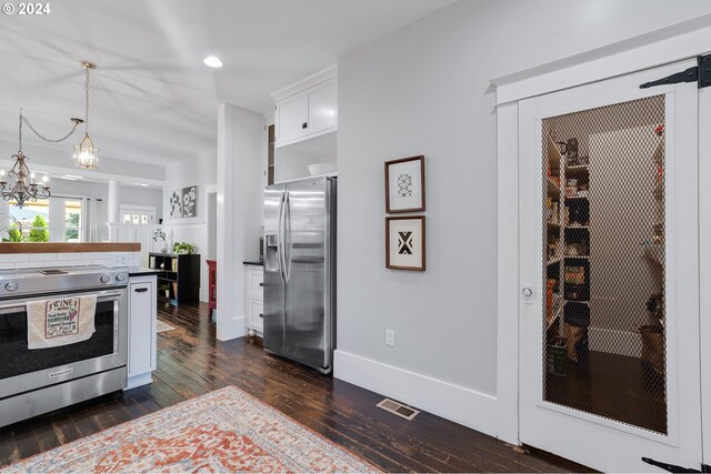 kitchen with visible vents, appliances with stainless steel finishes, dark wood-type flooring, hanging light fixtures, and white cabinetry