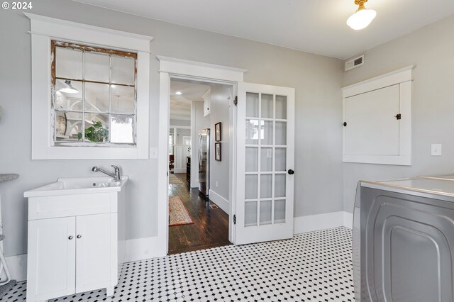 washroom with cabinet space, visible vents, baseboards, washer / clothes dryer, and a sink