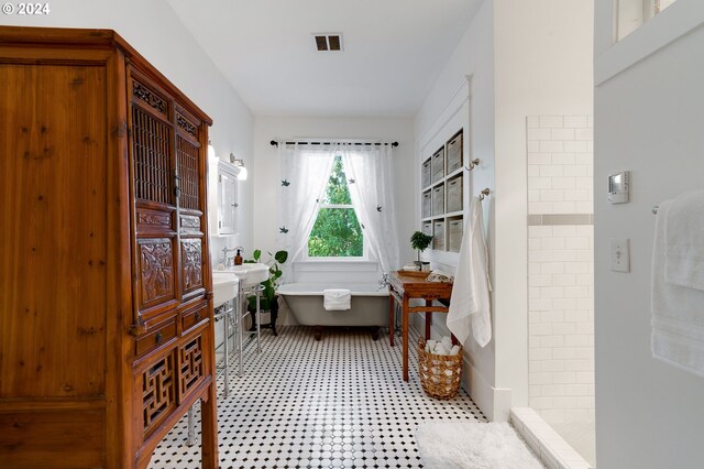 bathroom featuring tiled shower, a freestanding tub, and visible vents