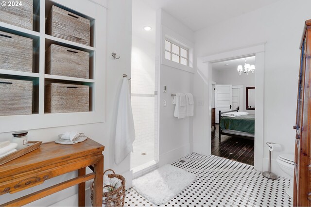 ensuite bathroom featuring a notable chandelier, toilet, ensuite bathroom, baseboards, and walk in shower