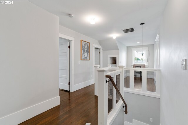 hall featuring visible vents, dark wood-type flooring, an upstairs landing, and baseboards