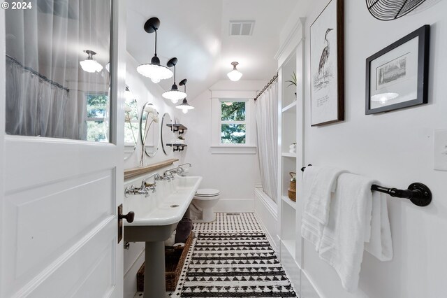 bathroom featuring toilet, shower / bath combo, visible vents, and baseboards