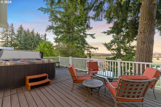 deck at dusk featuring a hot tub