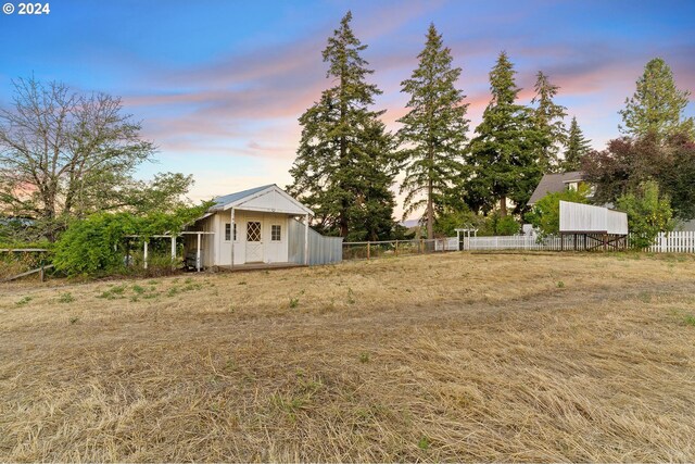 yard at dusk with an outdoor structure and fence