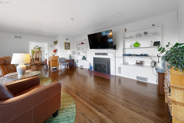 living room with built in shelves and dark hardwood / wood-style flooring