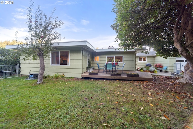 rear view of property featuring a lawn and a wooden deck