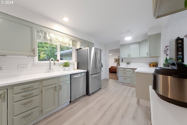 kitchen with light wood-type flooring, stainless steel appliances, backsplash, and sink