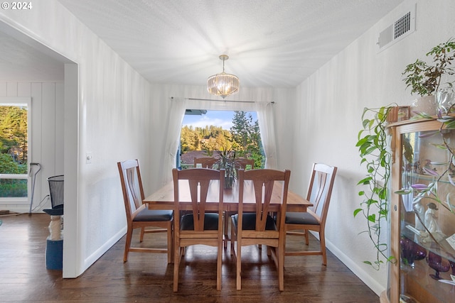 dining space with dark hardwood / wood-style floors, a textured ceiling, and a chandelier