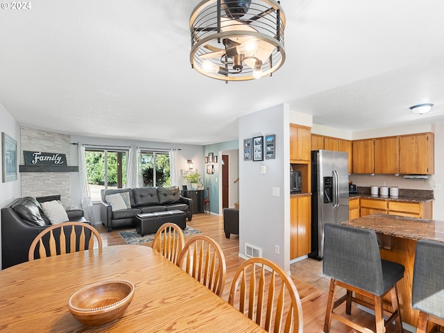 dining space featuring an inviting chandelier, a fireplace, and light hardwood / wood-style flooring