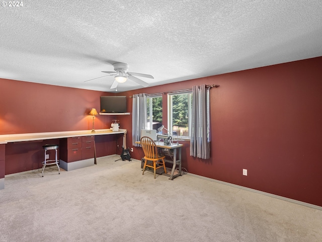 carpeted office space featuring a textured ceiling, built in desk, and ceiling fan