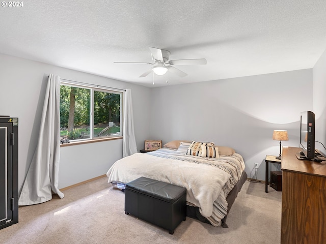 bedroom with ceiling fan, light carpet, and a textured ceiling