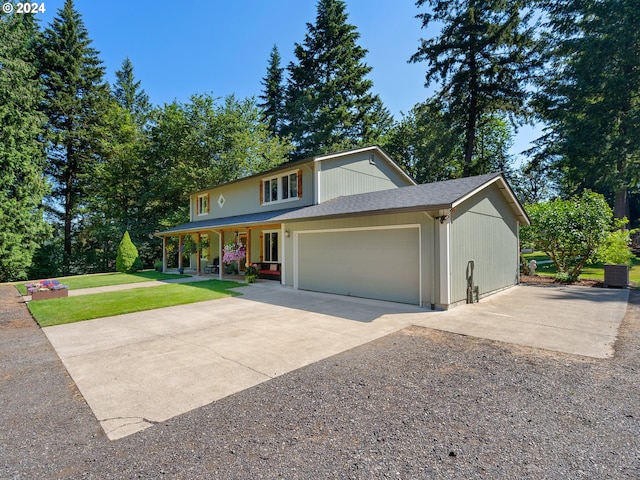 view of front of property with a garage, covered porch, and a front yard