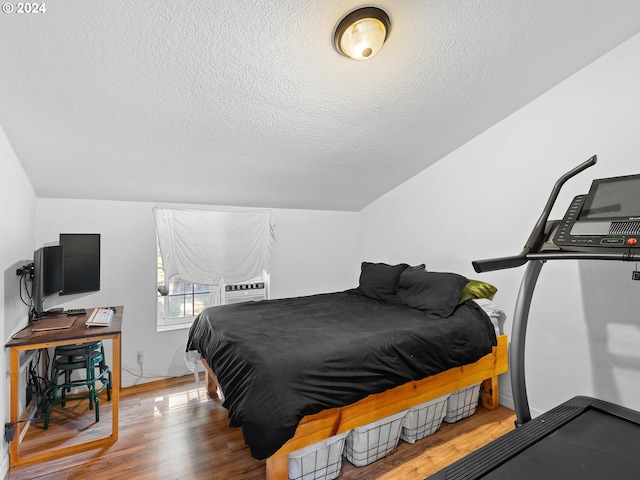 bedroom featuring hardwood / wood-style floors, a textured ceiling, and cooling unit